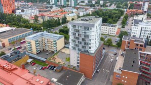 A cityscape with modern buildings, a parking lot, and a road. - New 2BR Apt with Sauna & Stunning Views  (Oulu)