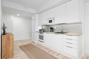 Una cocina moderna con armarios blancos, un horno de acero inoxidable, un microondas y un lavamanos.
