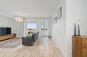 Una sala de estar moderna con sofá, televisor y piso de madera.