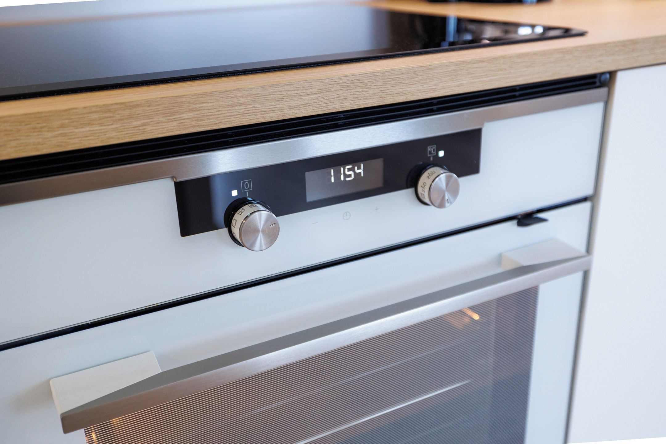 Een keuken met een moderne kookplaat, een digitaal display en twee bedieningsknoppen.