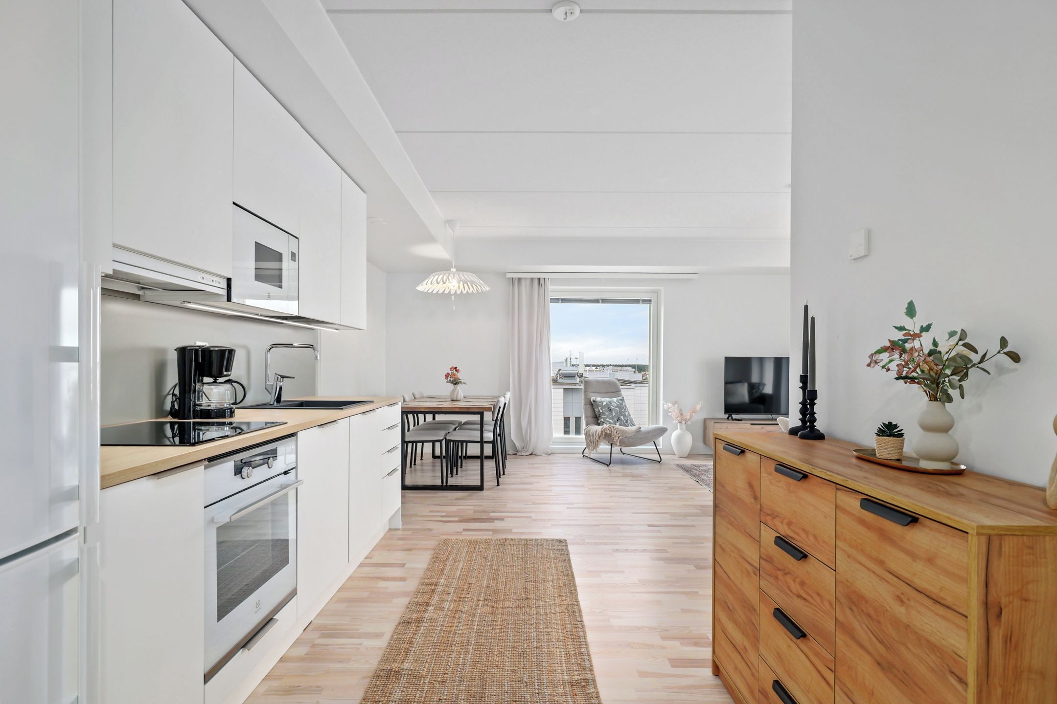 Una cocina moderna con armarios blancos, encimera de madera y horno empotrado.