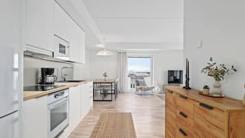 Una cocina moderna con armarios blancos, encimera de madera y horno empotrado.
