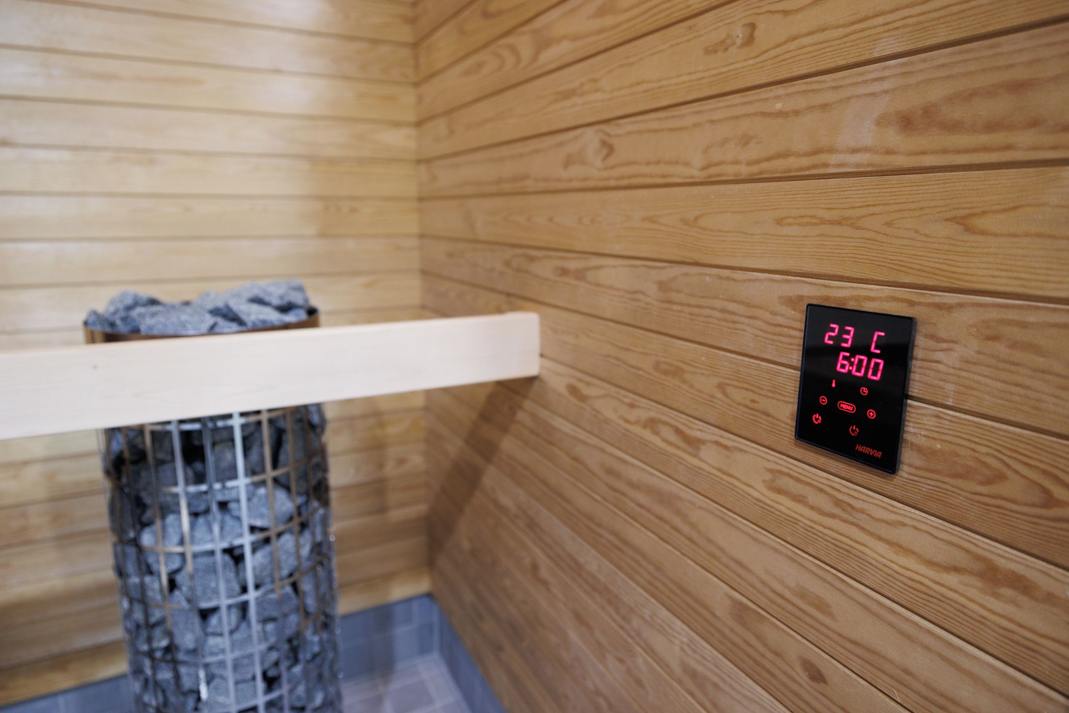 A sauna with a wooden interior, a digital display showing temperature and time, and a bench with a towel.
