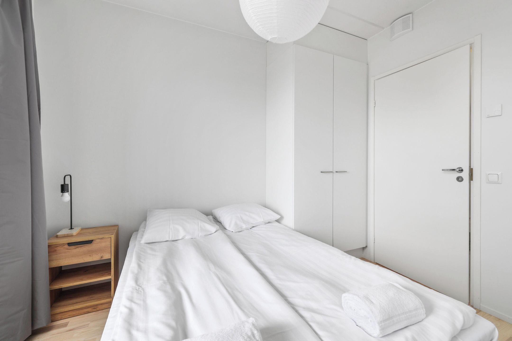 Un dormitorio minimalista con una cama individual, una mesita de noche y un armario.