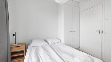 Un dormitorio minimalista con una cama individual, una mesita de noche y un armario.