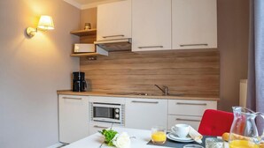 Eine moderne Küche mit weißen Schränken, einem Einbauofen, einer Mikrowelle und einer Kaffeemaschine.
