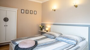 Ein Schlafzimmer mit Bett, Kleiderschrank, Wandleuchten und gerahmten Bildern.