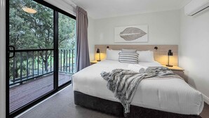 A bedroom with a large bed, a view of trees through a sliding door, and a ceiling light. - Villa Boronia - 2 Bedroom Villa at Cypress Lakes Resort (POKOLBIN)