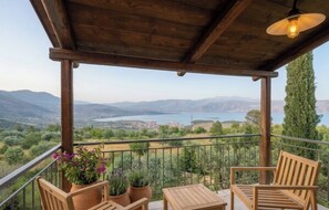 A wooden balcony with a view of a lake and mountains, furnished with chairs and tables. - Olive House Villa Galaxidi (Galaxidi)