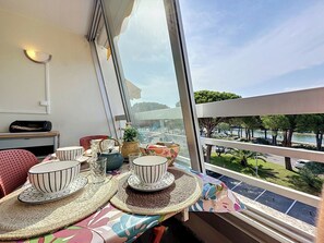 Ein Balkon mit Tisch, der für Tee gedeckt ist, einem Stuhl und Blick auf einen Park und Wasser.