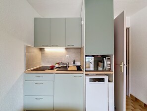 A compact kitchen with light-colored cabinets, a microwave, and a dishwasher. - La Lagune by Interhome (Port Camargue)