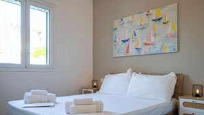 Ein Hotelzimmer mit einem Bett, zwei Nachttischen, einem Segelboot-Gemälde und einem Fenster.