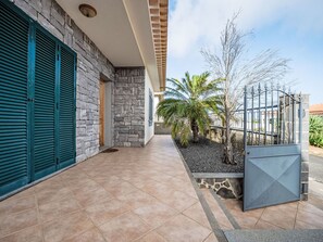 A building with a stone facade, a tiled patio, and a metal gate. - Villa Rosa by Interhome (Porto Santo)