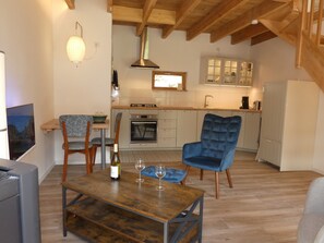 Een moderne keuken met houten kastjes, een ingebouwde oven en een eethoek met een tafel en stoelen.