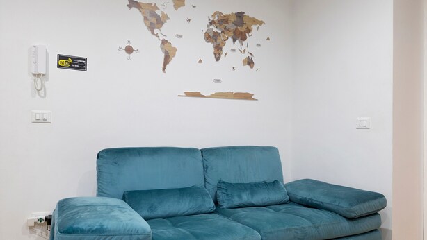 Een kamer met een blauwe bank, een wereldkaart aan de muur, een Wi-Fi symbool en een telefoon.