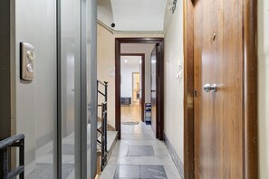 Un corridoio con una porta in legno, una porta in vetro e una scala.