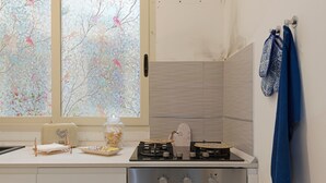 Een keuken met een gasfornuis, oven en een raam met uitzicht op bomen.