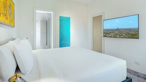 Una camera d'albergo con un letto, una televisione fissata al muro e un ingresso che conduce al bagno.