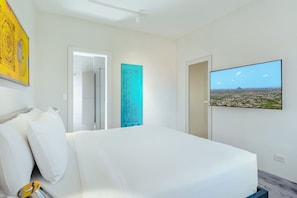 Ein Hotelzimmer mit Bett, Wandfernseher und Tür zu einem Badezimmer.