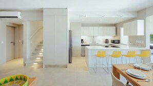 Una cucina moderna con isola centrale, elettrodomestici integrati e zona pranzo con sedie gialle.