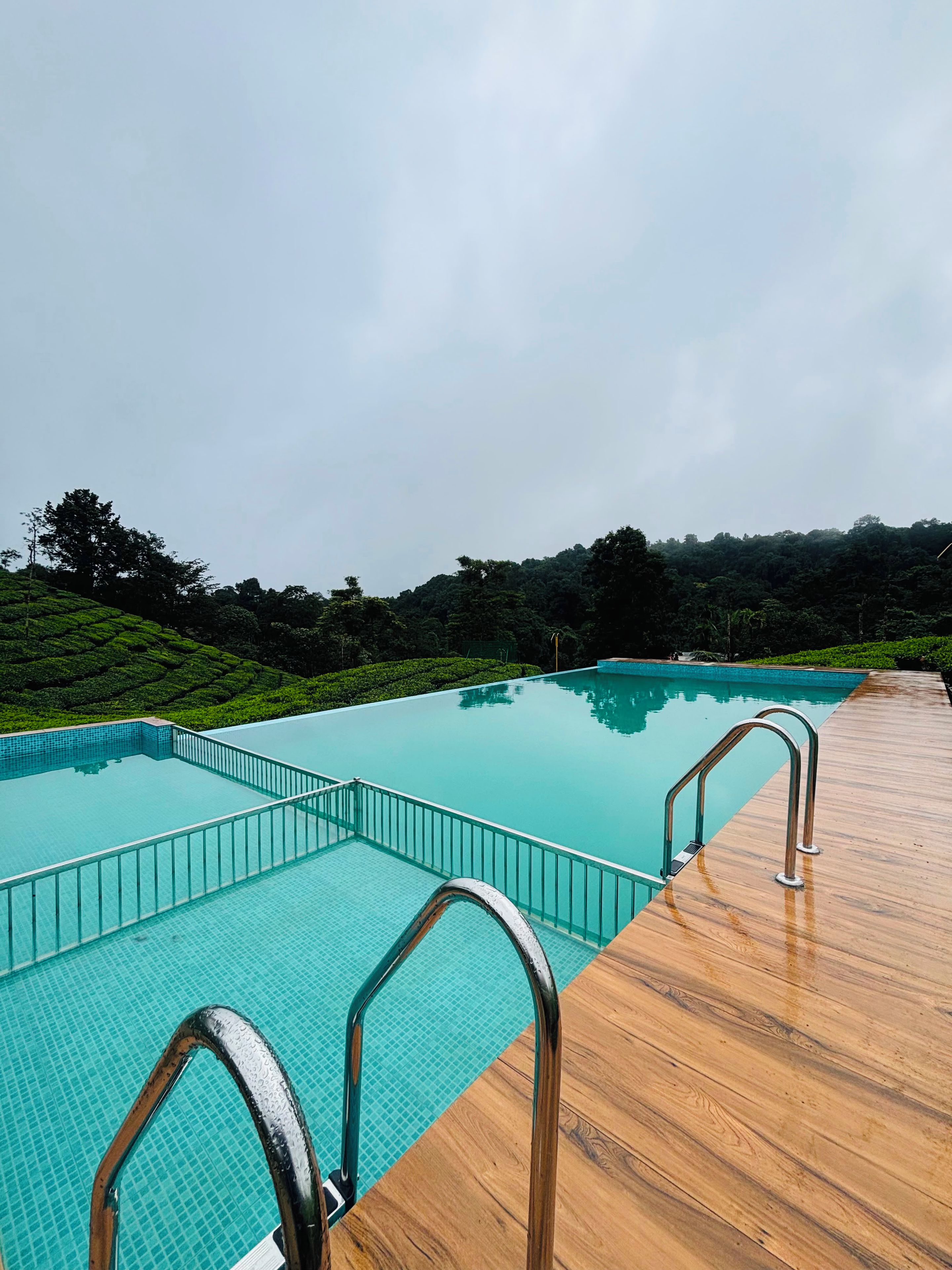A swimming pool with a wooden deck and metal railings.