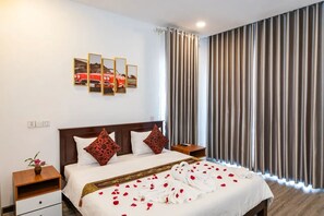 A hotel room with a bed, a nightstand, a wall-mounted picture, and a window with curtains. - Sreng Angkor Hotel (Krong Siem Reap)