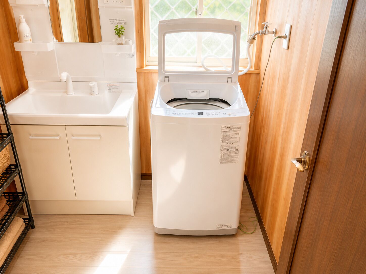 Une petite cuisine équipée d’un lave-linge, d’un évier et d’une étagère où sont rangés les produits de toilette.