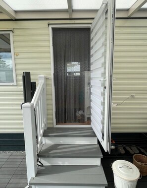 A covered outdoor area with a set of steps leading to a door with a vertical striped pattern. - Kamperland Beach Resort - 524 (Kamperland)