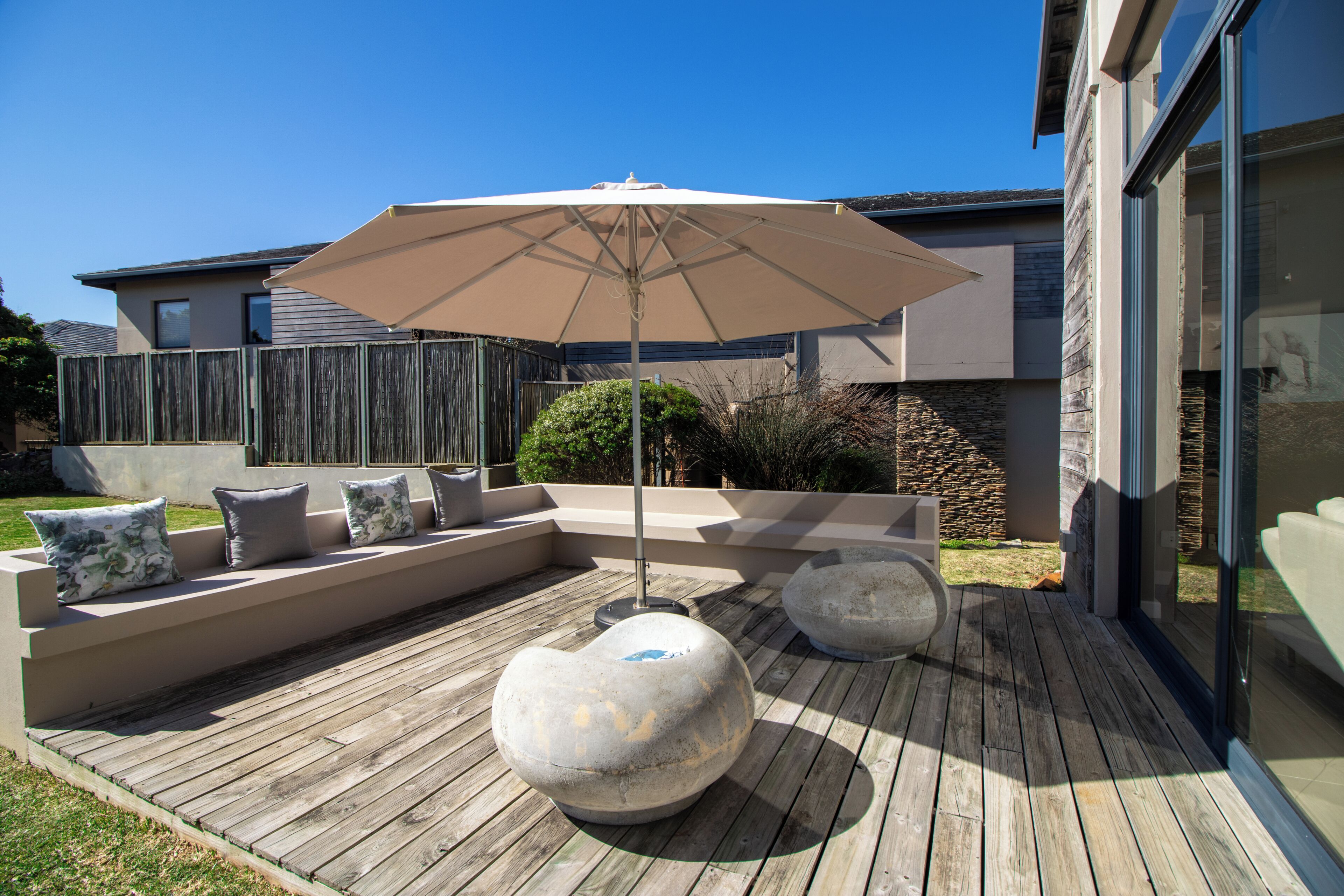 Een houten terras met een ingebouwde bank en een grote parasol.