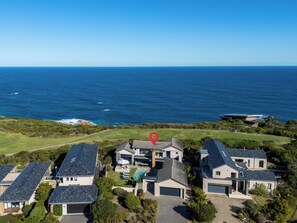 A residential area with houses, a golf course, and the ocean in the background. - Sea Through House (Knysna)