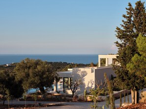A modern building with a view of the sea, surrounded by trees and a clear sky. - Luxury 6-bedroom villa in north Zakynthos | Private pool & sea views (Korithi)