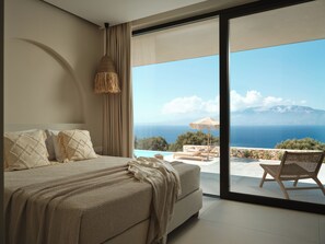 A bedroom with a large bed, a view of the sea, and a balcony with a chair. - Luxury 6-bedroom villa in north Zakynthos | Private pool & sea views (Korithi)