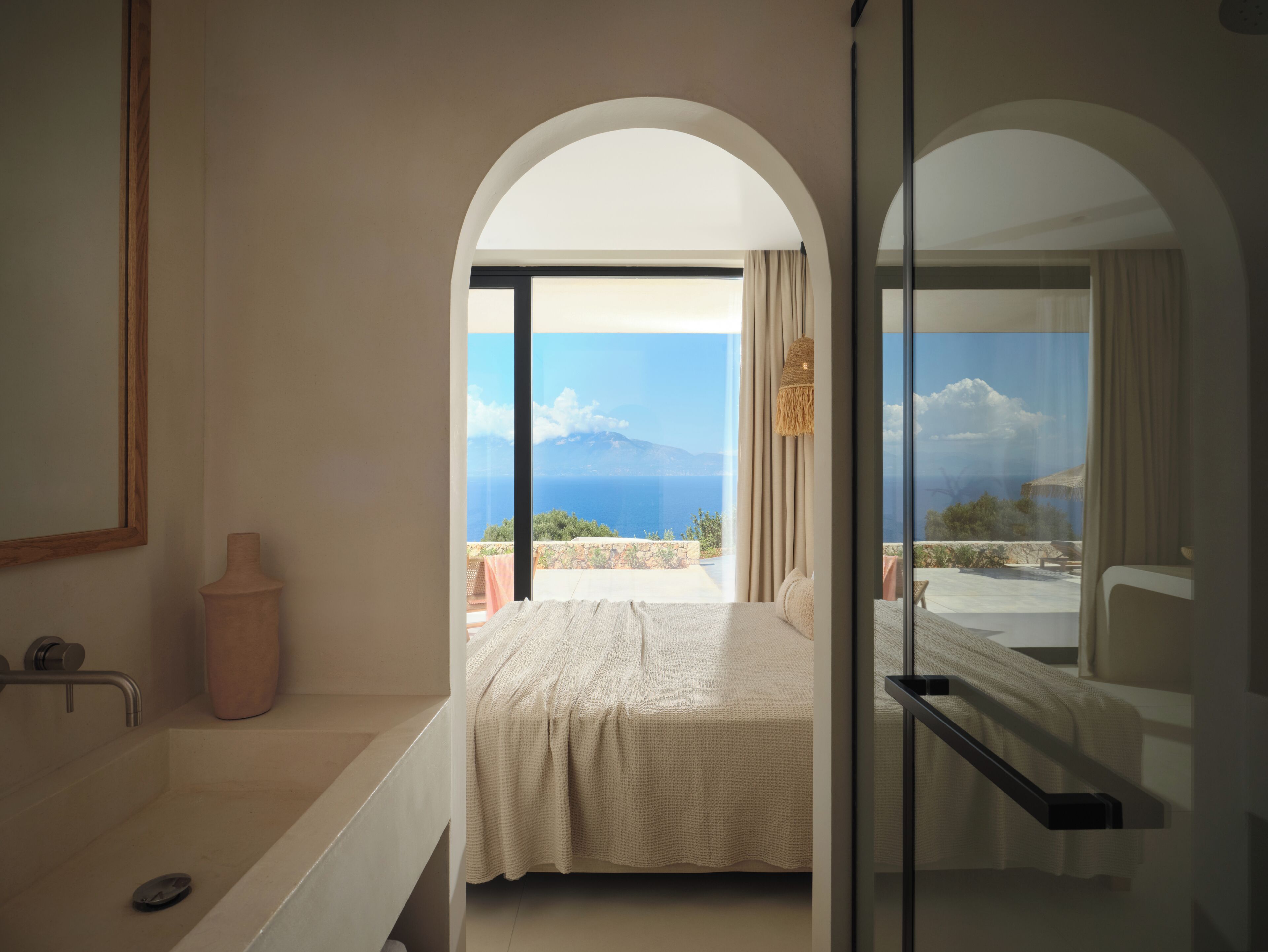 Quarto com cama, banheiro com banheira e vista para o mar.