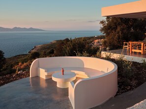 A modern outdoor seating area with a circular design, overlooking a coastal landscape with a view of the sea and distant mountains. - Luxury 6-bedroom villa in north Zakynthos | Private pool & sea views (Korithi)