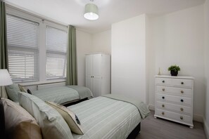 A bedroom with two beds, a wardrobe, and a dresser. - Free Parking | Near Beach | Pets OK | Sleeps 5 (Blackpool)