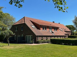 Een woonhuis met twee verdiepingen, een schuin dak, een voordeur en een zichtbare garage.