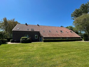 Een huis met twee verdiepingen, een schuin dak, een klein voortuintje en een verzorgd gazon.