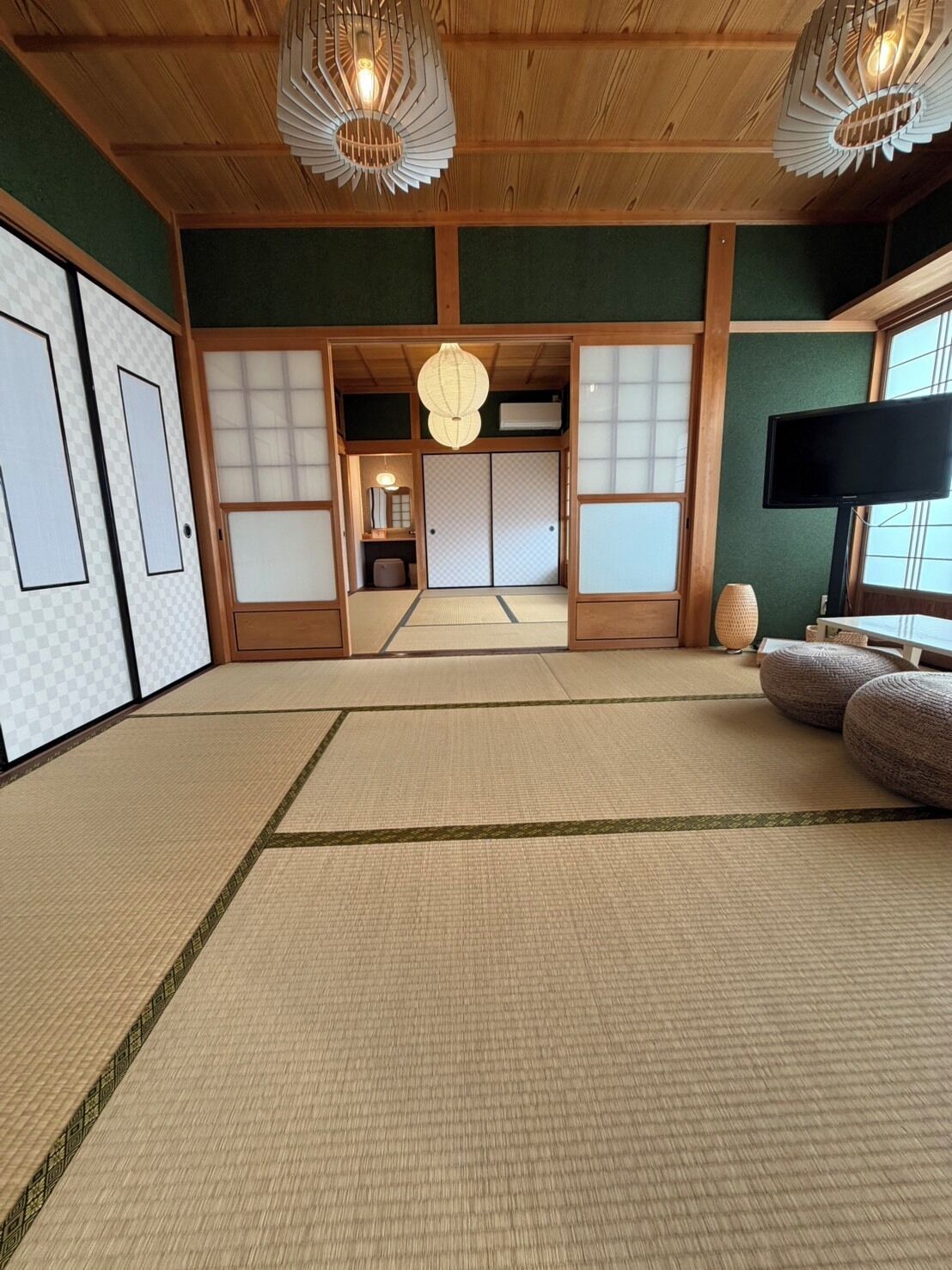 Una stanza tradizionale giapponese con pavimenti in tatami, porte scorrevoli e un televisore.