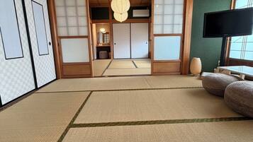 Una stanza tradizionale giapponese con pavimenti in tatami, porte scorrevoli e un televisore.
