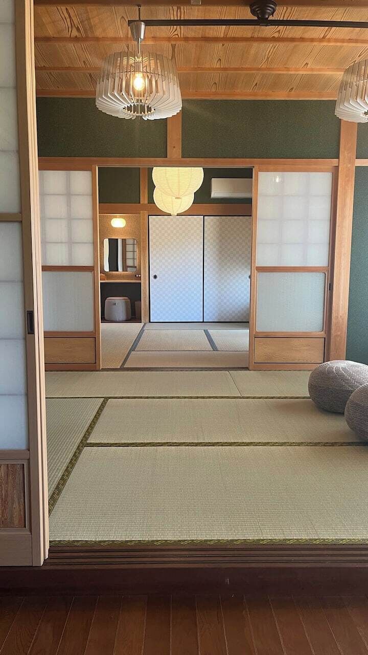 Une pièce de style japonais traditionnel, avec un sol recouvert de tatamis, des portes coulissantes et un luminaire suspendu.