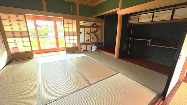 Une pièce avec un sol recouvert de tatamis, dotée de portes coulissantes, d’un paravent japonais traditionnel et d’une petite table avec un éventail.