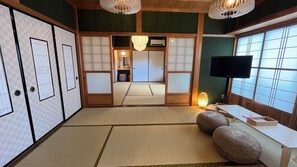 Ein traditioneller japanischer Raum mit Tatami-Boden, Shoji-Schirmen, einem Fernseher und einem Futon.