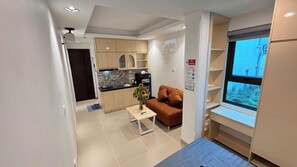 Un espacio habitable compacto con kitchenette, un sofá, una mesita y ventana con vistas.