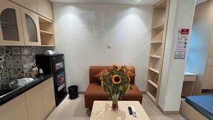 Um espaço compacto com cozinha compacta, um sofá com um vaso de girassóis e uma cama.
