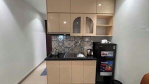 Cozinha compacta com bancada preta, pia e geladeira com a marca Funiki.