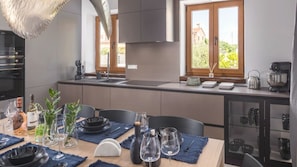 Eine moderne Küche mit Essbereich, gedeckter Tafel, großem Fenster, integrierten Geräten und einer aufgeräumten Anordnung.