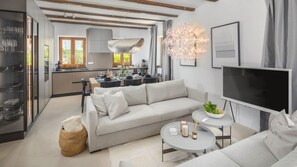 Ein modernes Wohnzimmer mit einer Couch, einem Fernseher und einem Essbereich im Hintergrund.