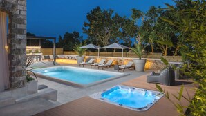 A swimming pool with lounge chairs and a hot tub, surrounded by stone walls and trees. - Vila Aurelia by Villas Guide (Cabrunici)