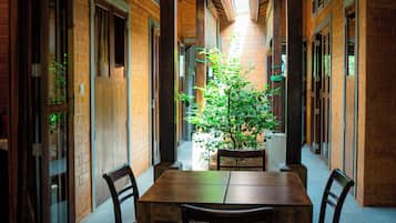 Un largo pasillo con una mesa y sillas centrales, flanqueado por paredes de ladrillo y vigas de madera.
