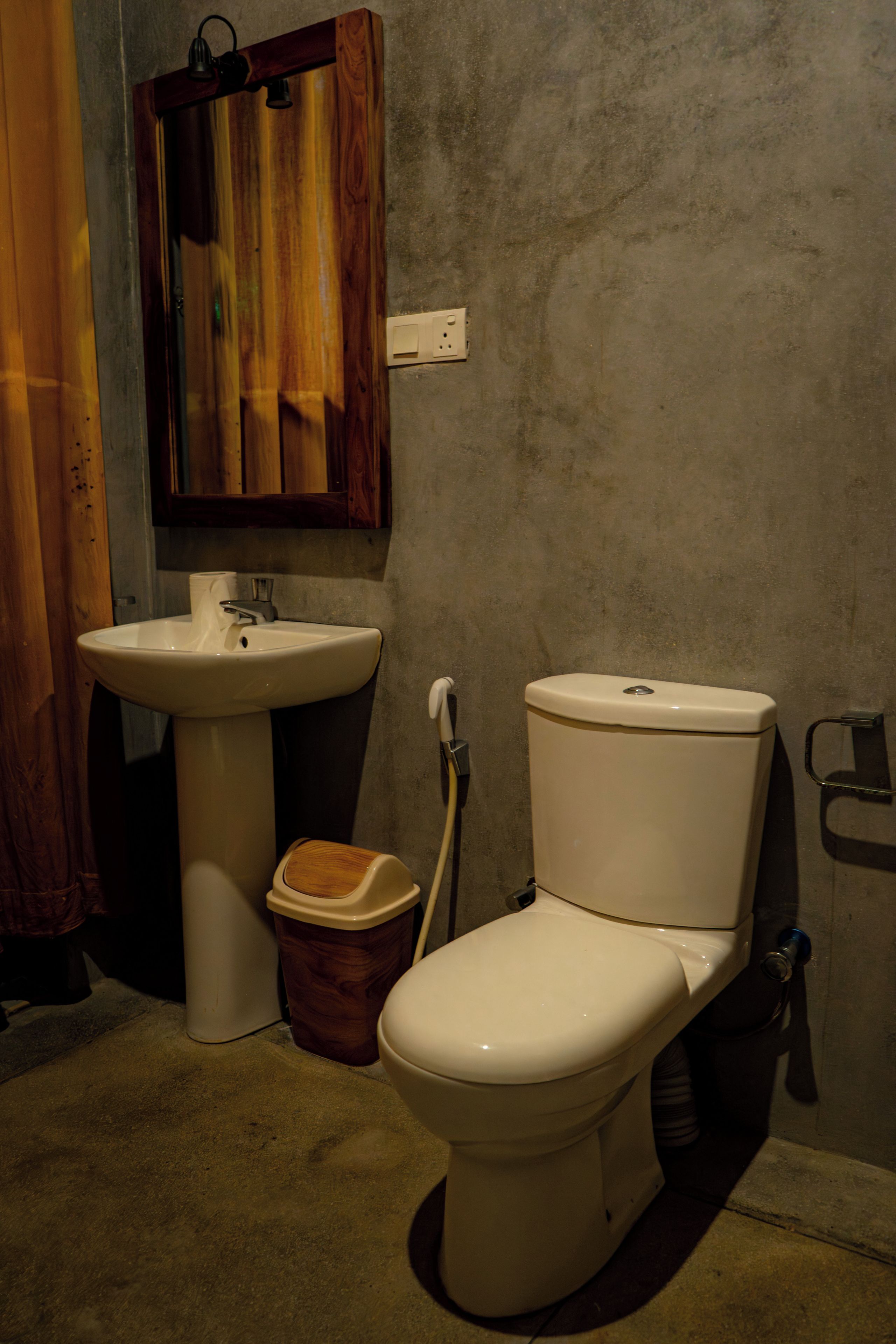A bathroom with a toilet, sink, and wooden cabinet.